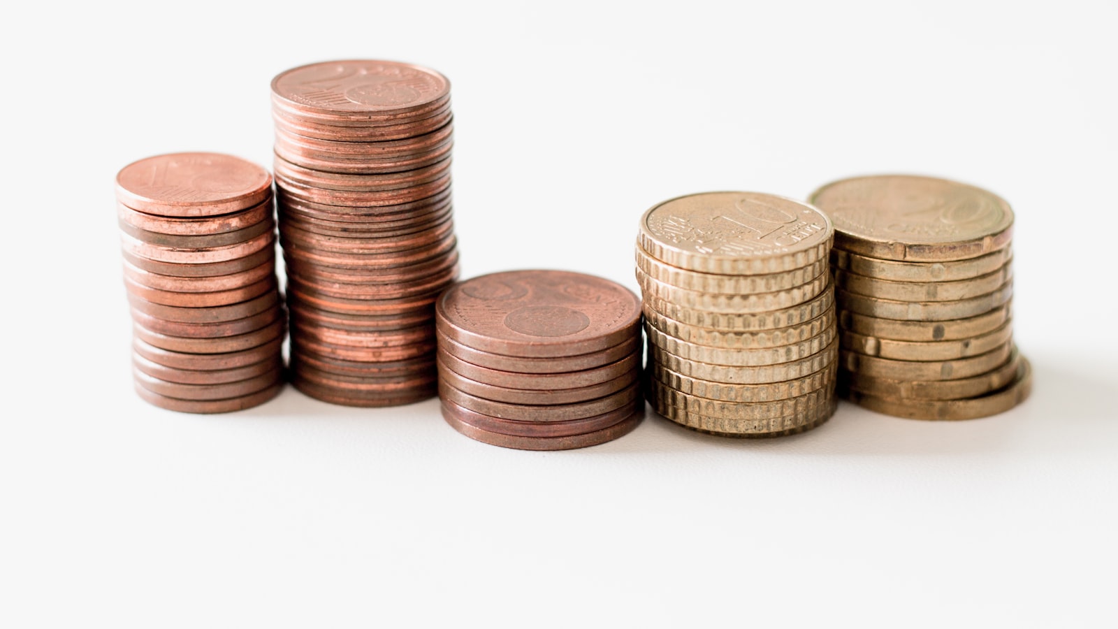 Stacked gold-colored coins on a white surface - alternatives to European bank savings that beat 2% deposit rates in 2026.