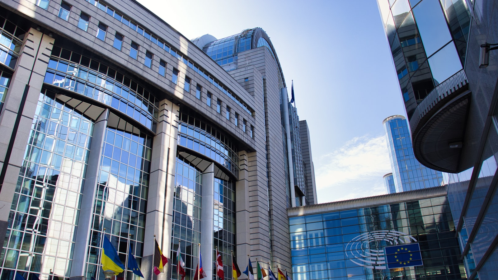 Modern EU parliament building with flags and sky in Brussels - the institutions behind ECSP and MiFID II rules.